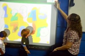 A lousa multimídia interage com o toque da criança.